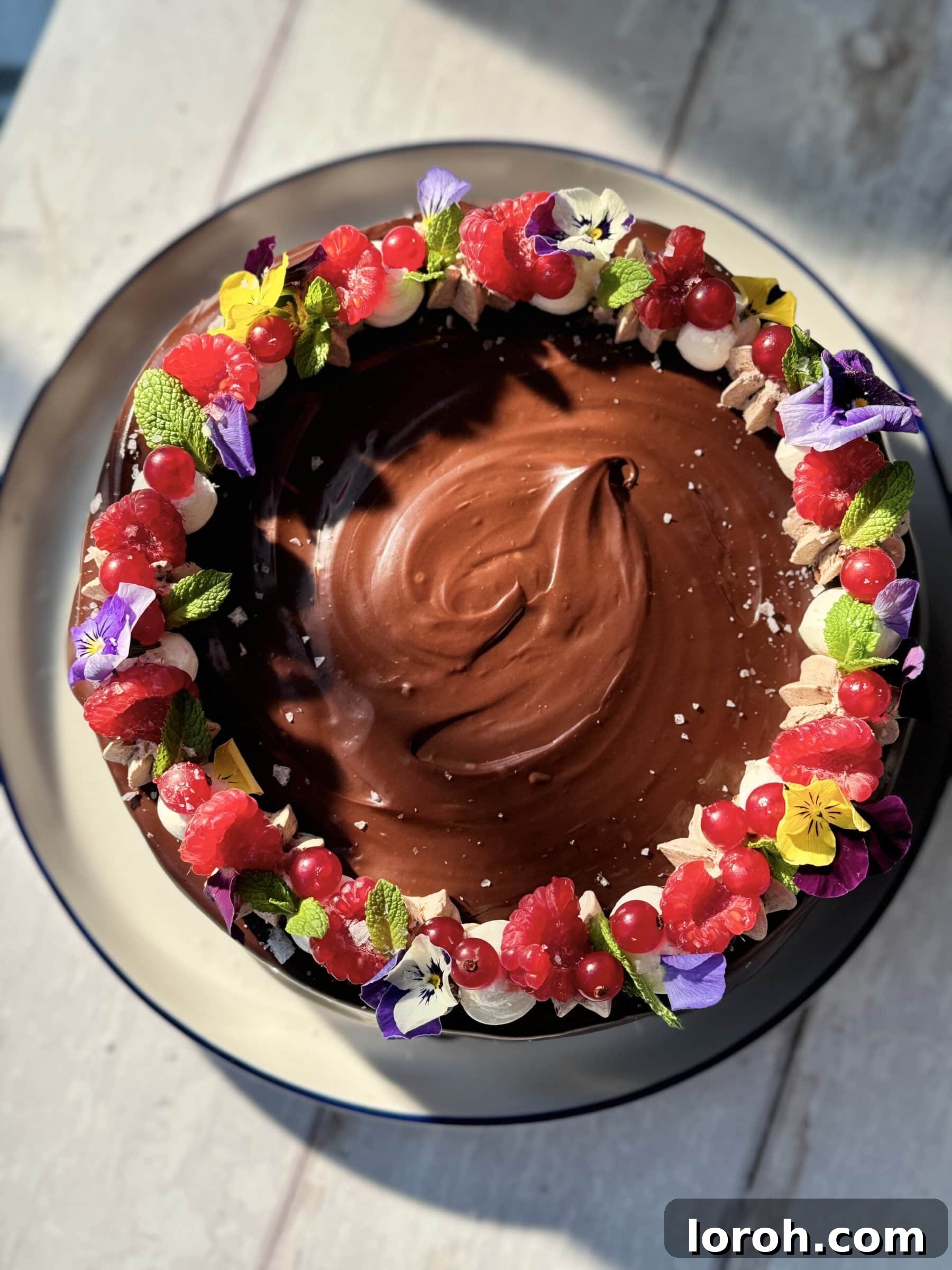 A full view of the magnificent chocolate cake with chocolate mousse, garnished with edible flowers and fresh fruit.