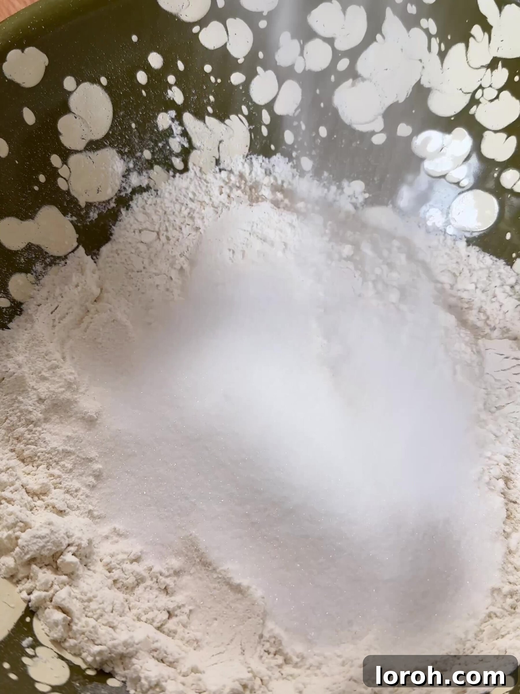 Sifting dry ingredients including flour, baking powder, and sugar into a large mixing bowl.