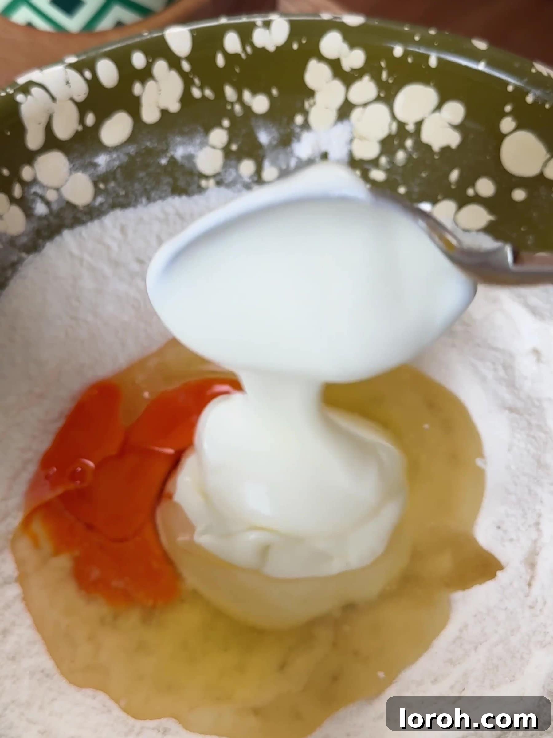 Adding yogurt, egg, and vegetable oil to the sifted dry ingredients in a bowl.