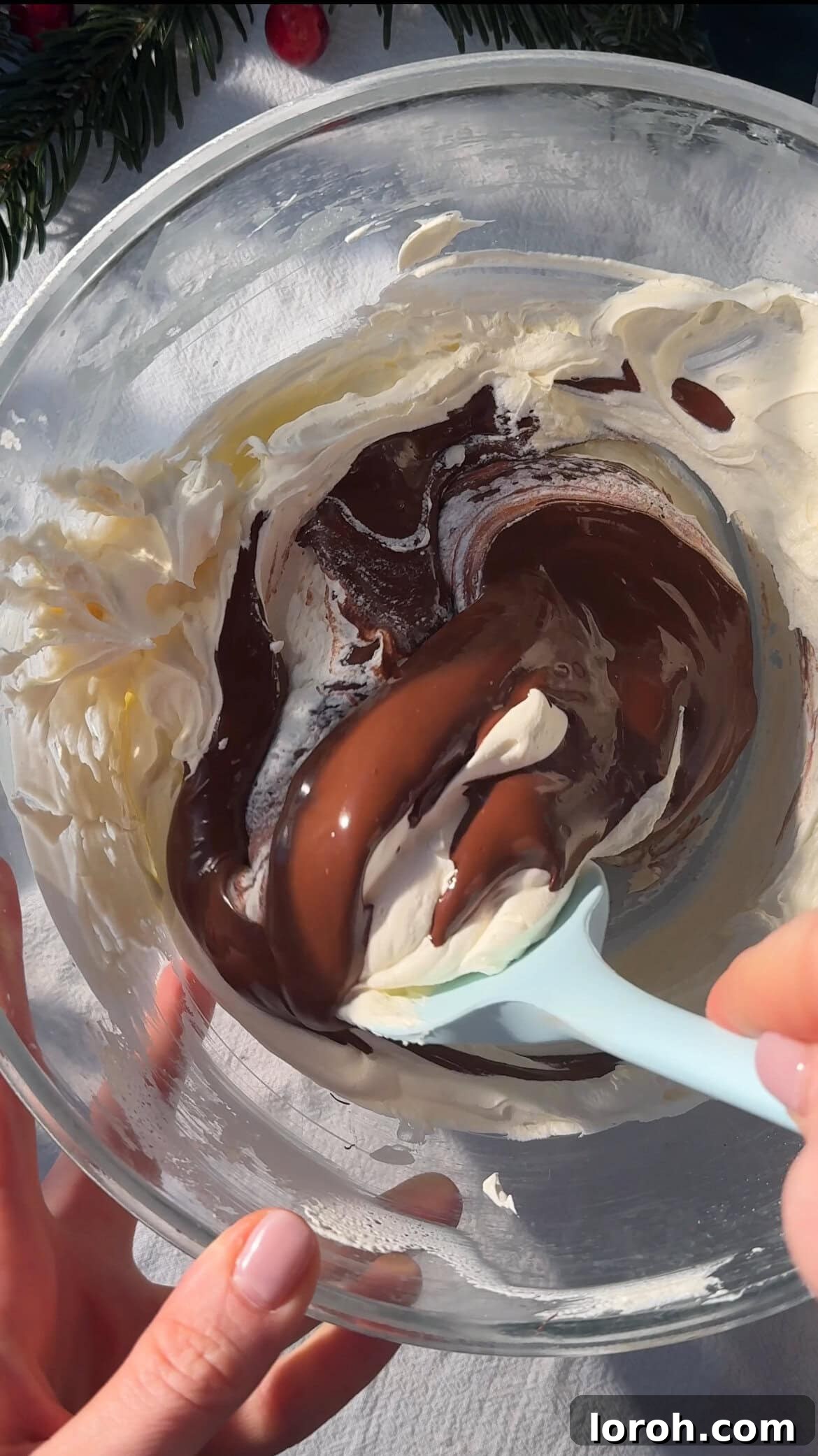 Gently folding melted chocolate into whipped cream until fully combined.
