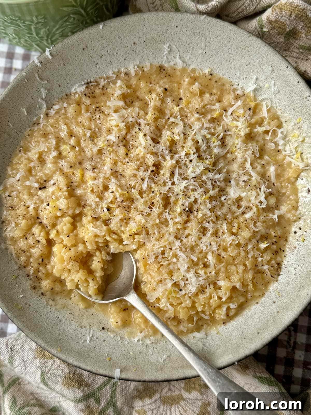 Velvety Easy Pastina 2 A bowl of creamy pastina with a spoon, garnished with fresh herbs and a slice of lemon.
