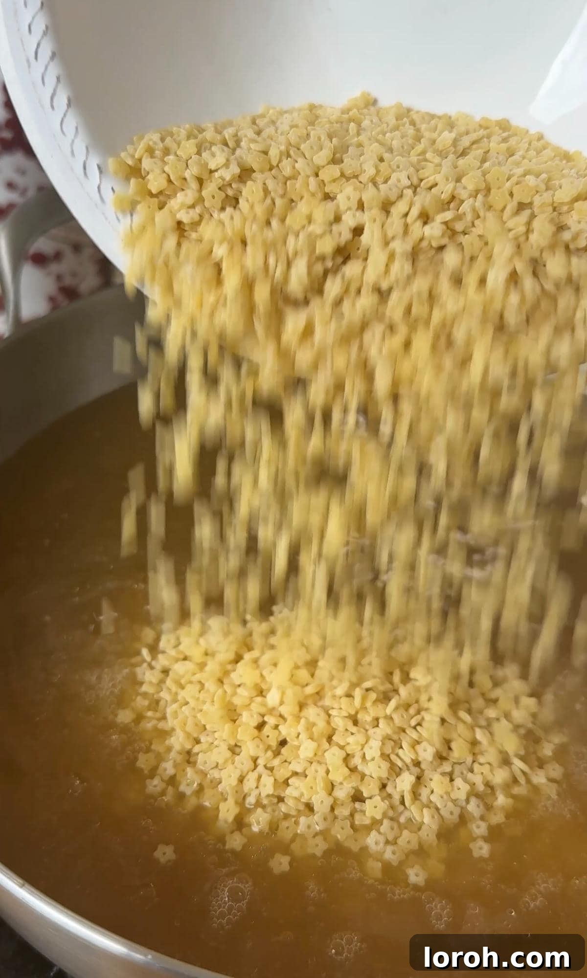 Velvety Easy Pastina 5 Pouring pastina into the gently boiling chicken stock.
