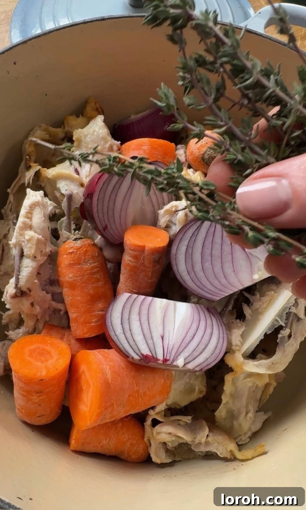 Adding chicken carcass, vegetables, and aromatics to a large stock pot.