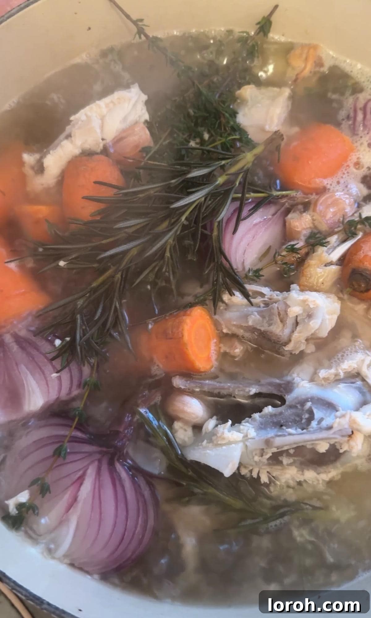Chicken stock gently simmering in a pot on the stovetop.