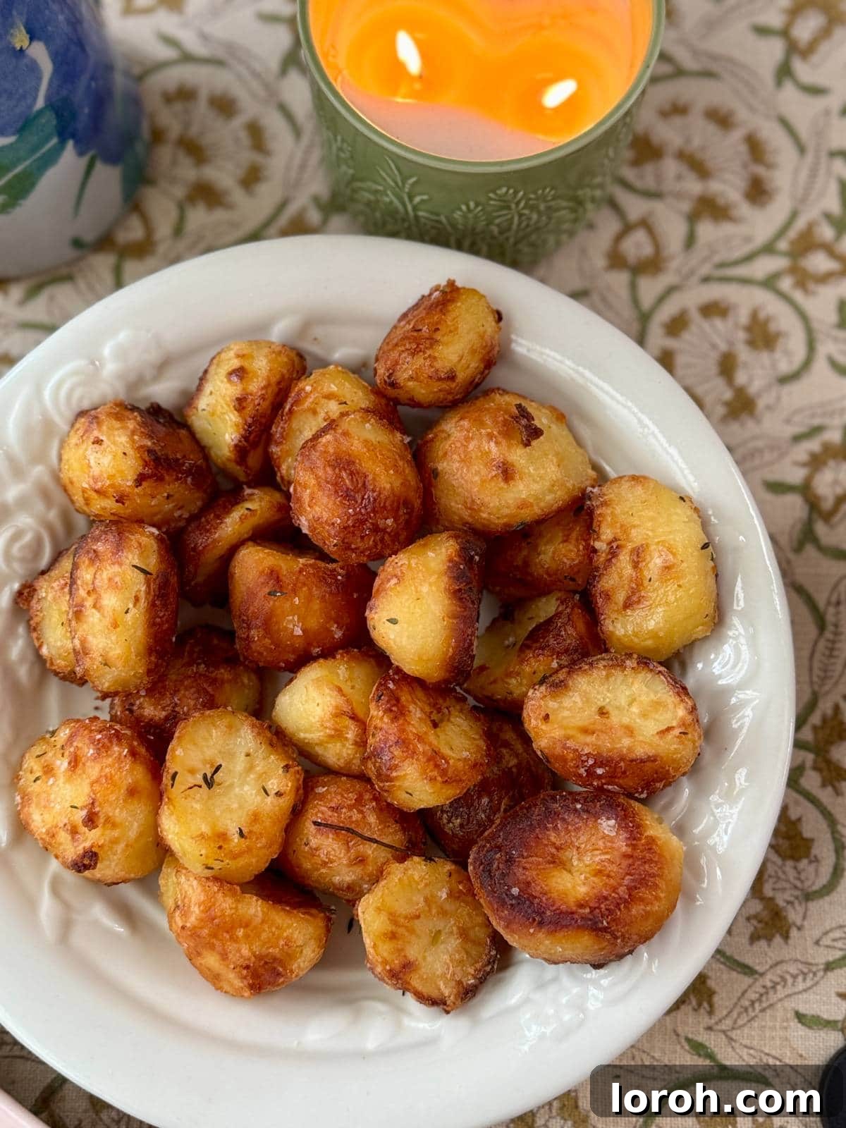 golden crispy roasted white potatoes with fresh rosemary in a white serving bowl, perfectly cooked.