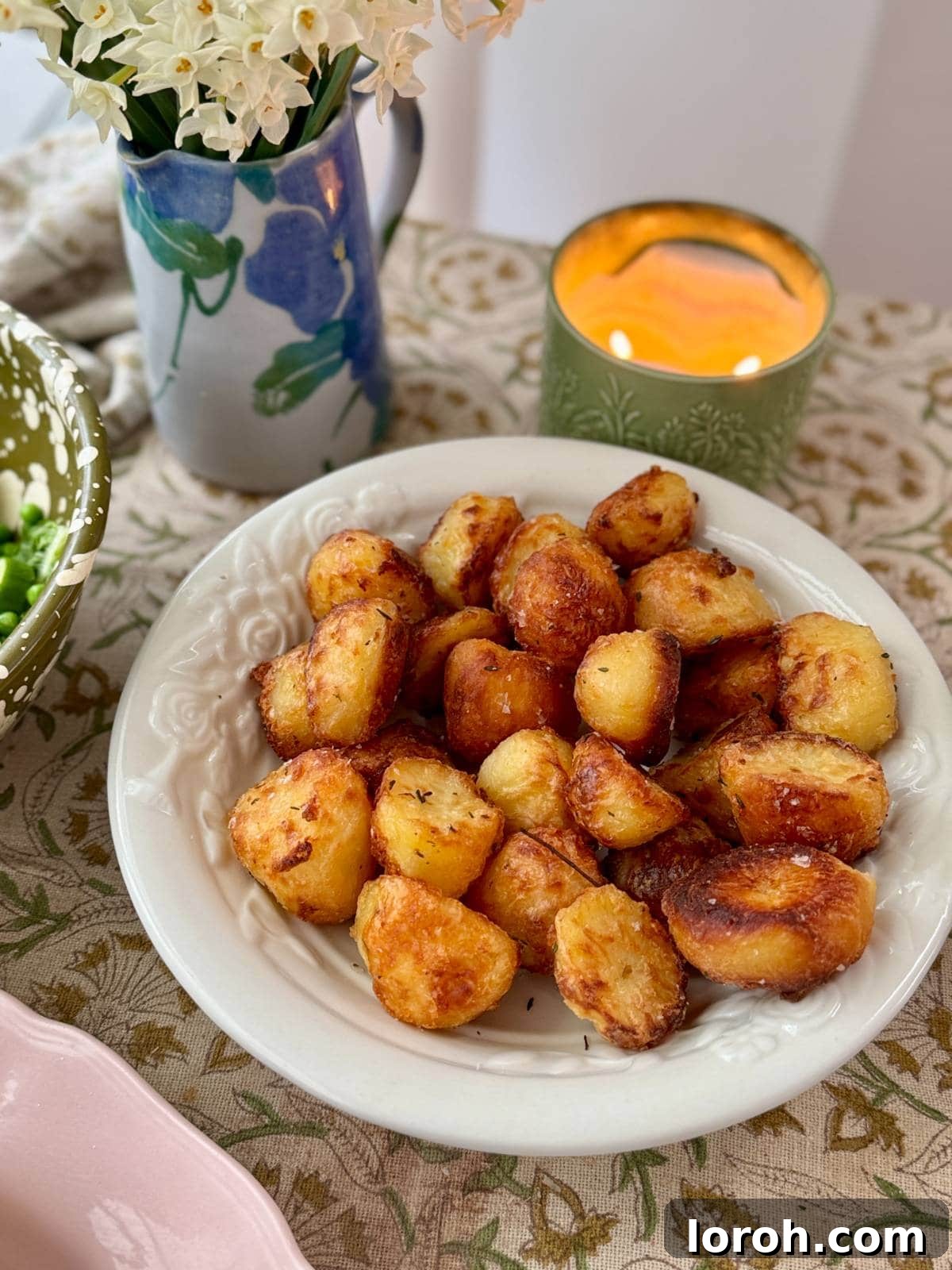 close-up of roasted white potatoes with rosemary in a white serving bowl, showing the crispy texture.