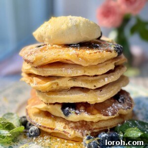 A magnificent stack of light and airy lemon ricotta blueberry pancakes, crowned with whipped honey butter.