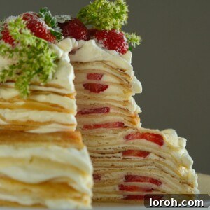 A cross-section view of a stunning Strawberry Mille Crêpe Cake, revealing delicate layers of crêpes, cream, and fresh strawberries.