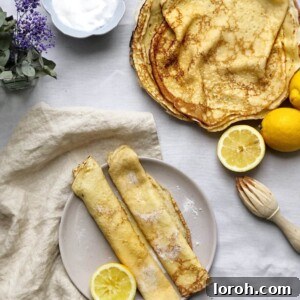 Traditional British pancakes served on a plate with fresh lemon halves and sugar, ready to be enjoyed.