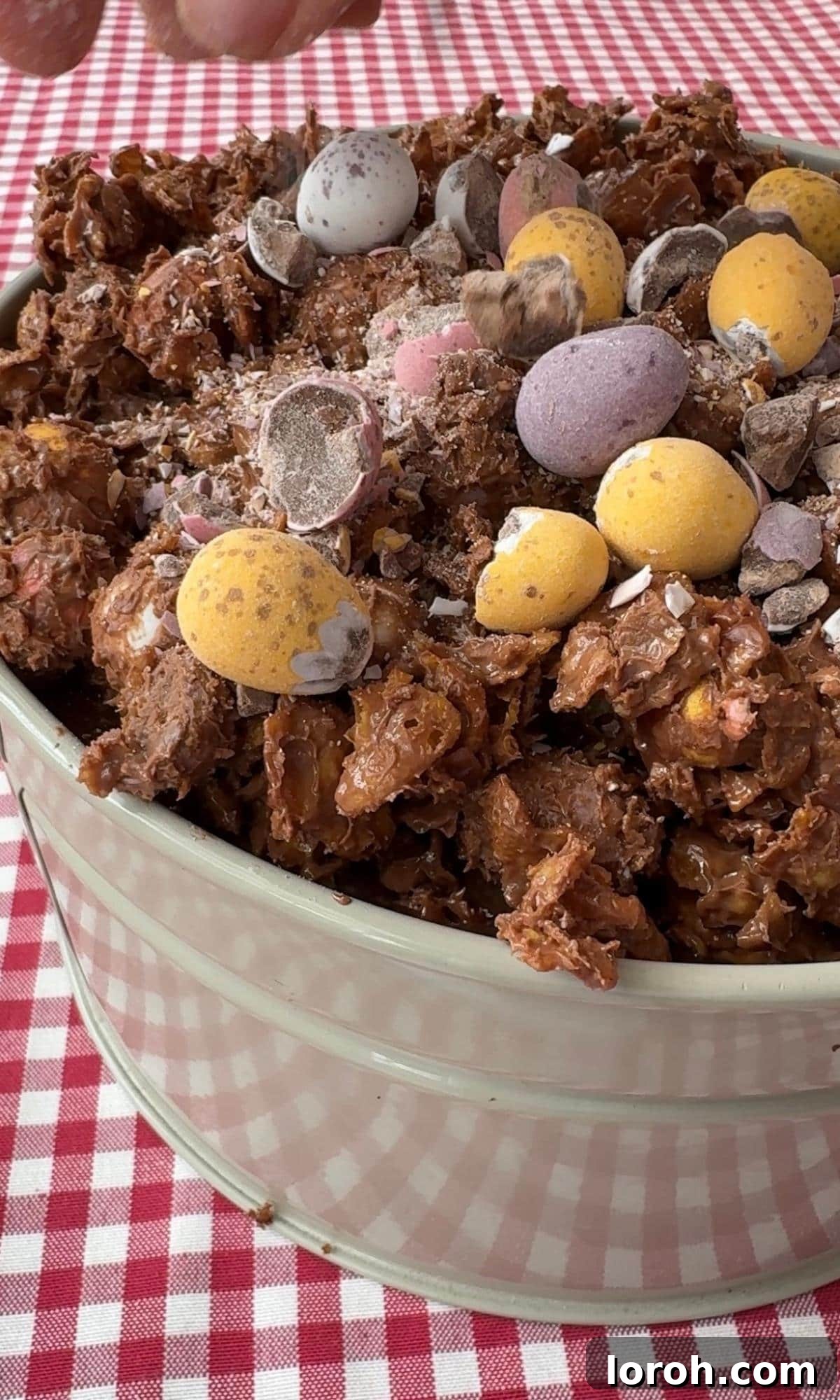 The final step of adding the crunchy cornflake topping and scattering the remaining mini eggs over the ganache layer.