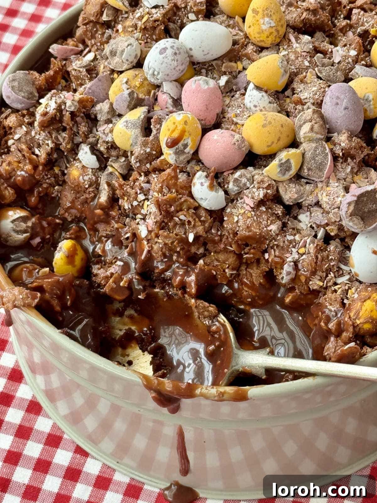 A delicious scoop being taken from the Cornflake Dream Cake, showcasing the inviting layers of chocolate cake, ganache, and crunchy cornflakes with mini eggs.