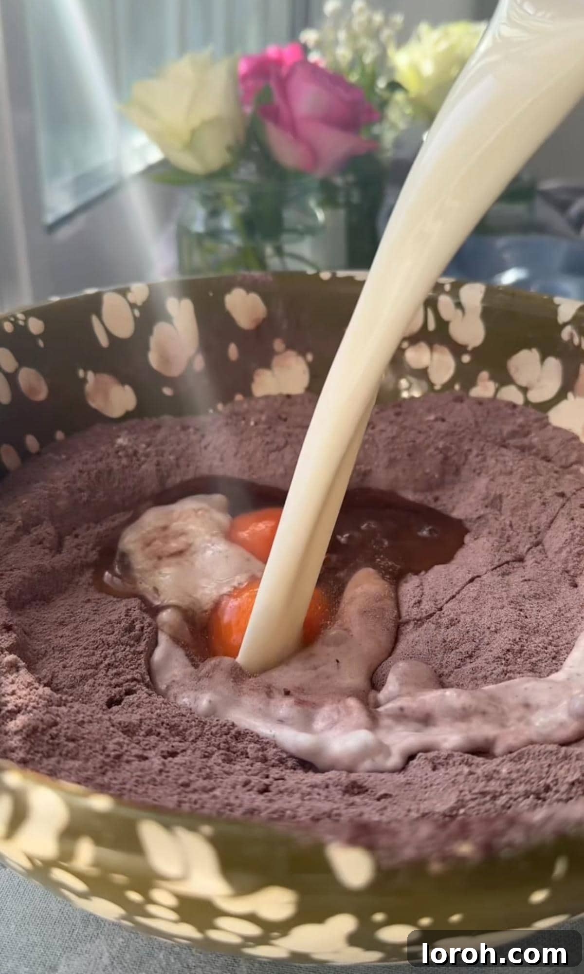 A visual of adding eggs and milk to the chocolate cake batter, illustrating the wet ingredients being combined with the dry.