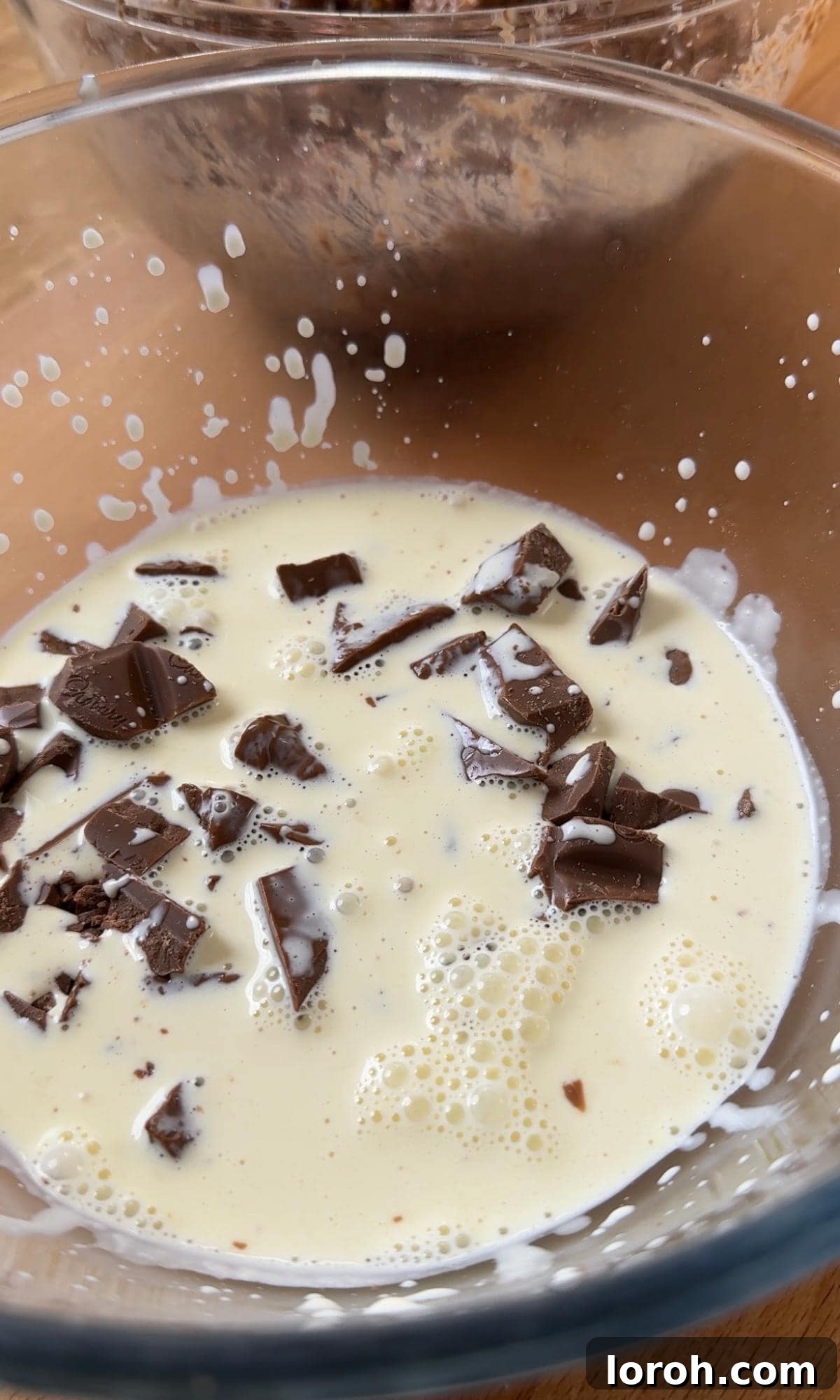 Close-up of smooth chocolate ganache in a bowl, ready to be poured over the cake.