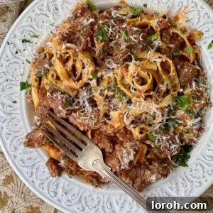 beef shin ragu with tagliatelle in a white bowl.
