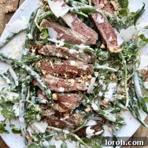 White serving platter with a steak and green bean caesar salad.