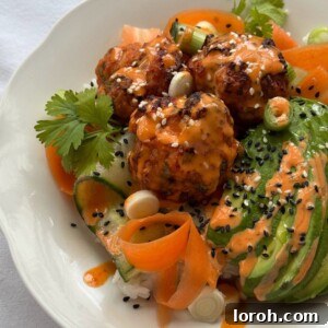 Close up of Korean flavoured salmon fishcakes served over rice with sliced avocado and a gochujang mayo drizzle.
