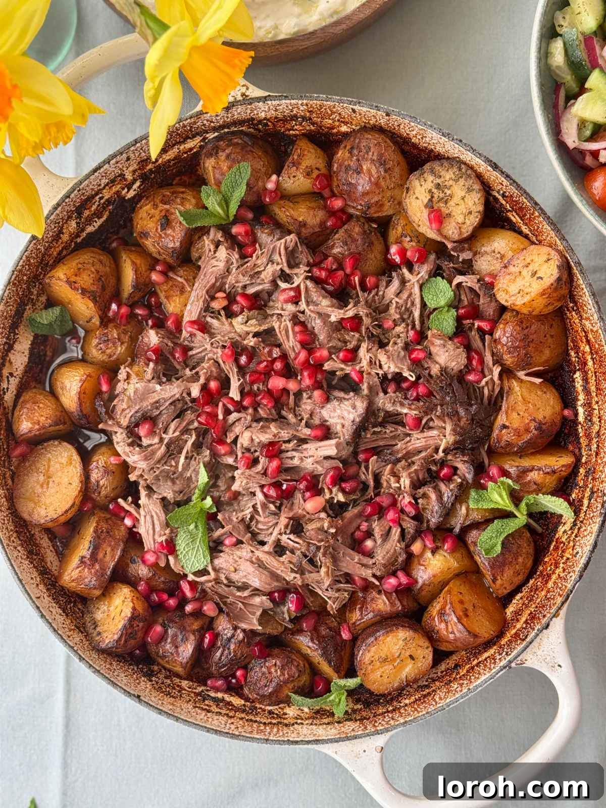 Close-up of the perfectly roasted slow cooked lamb with potatoes in the pan, showing the rich pan juices.