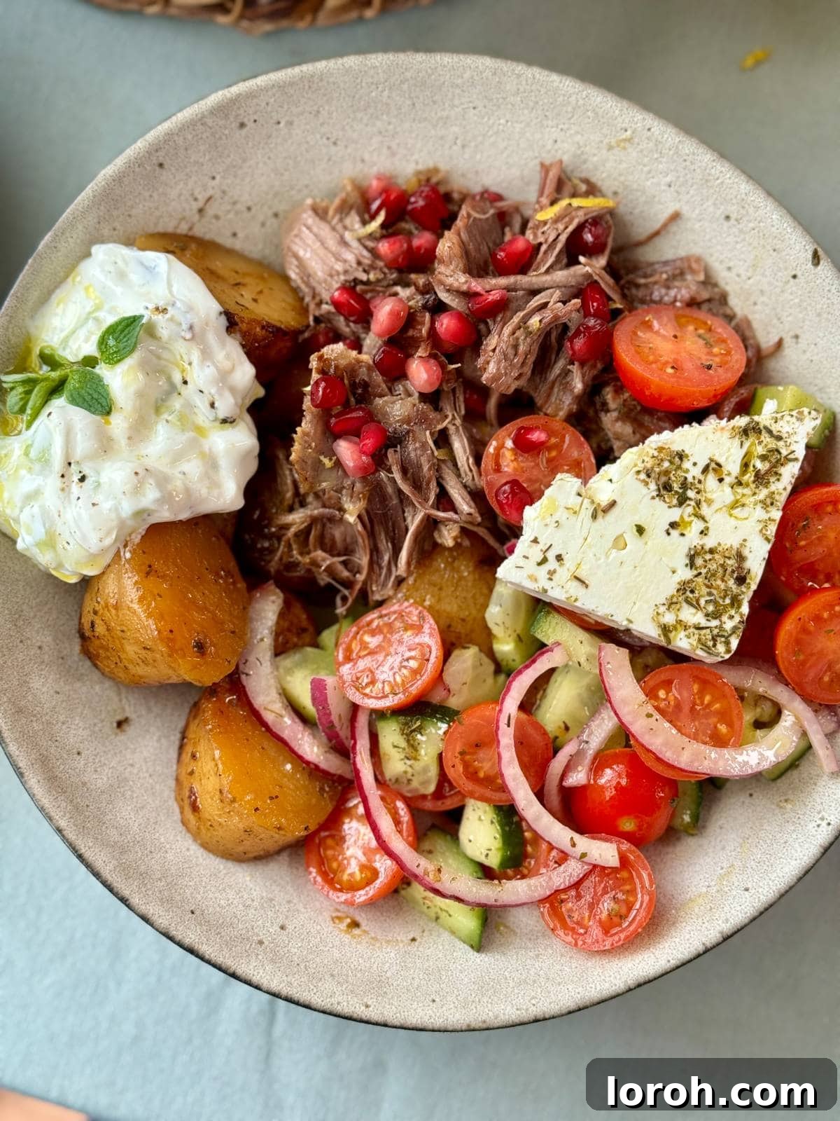 Slow cooked lamb with roasted baby potatoes and a side of Greek salad and tzatziki.