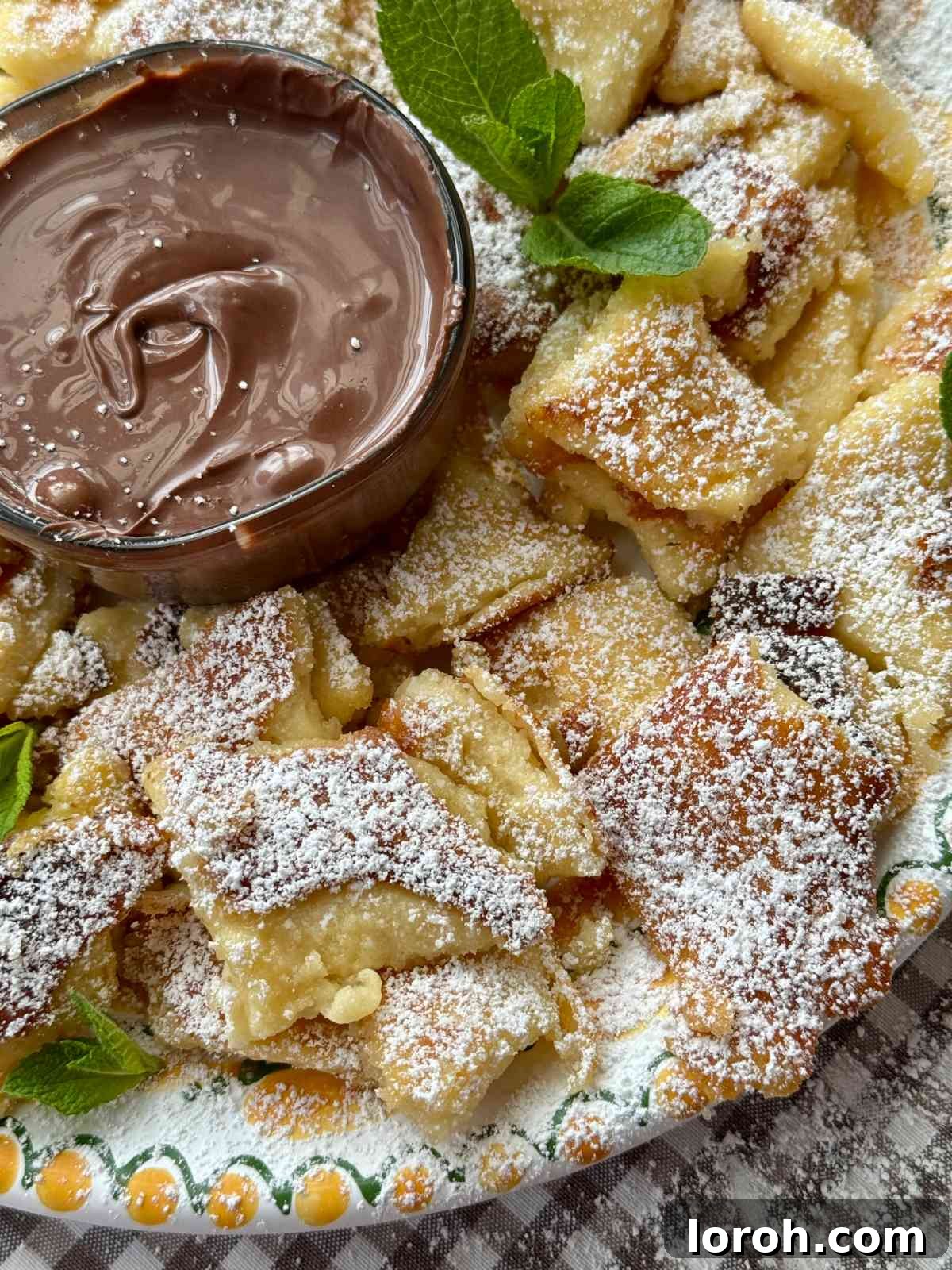 Kaiserschmarrn on a plate, generously dusted with powdered sugar and served alongside a vibrant plum compote.