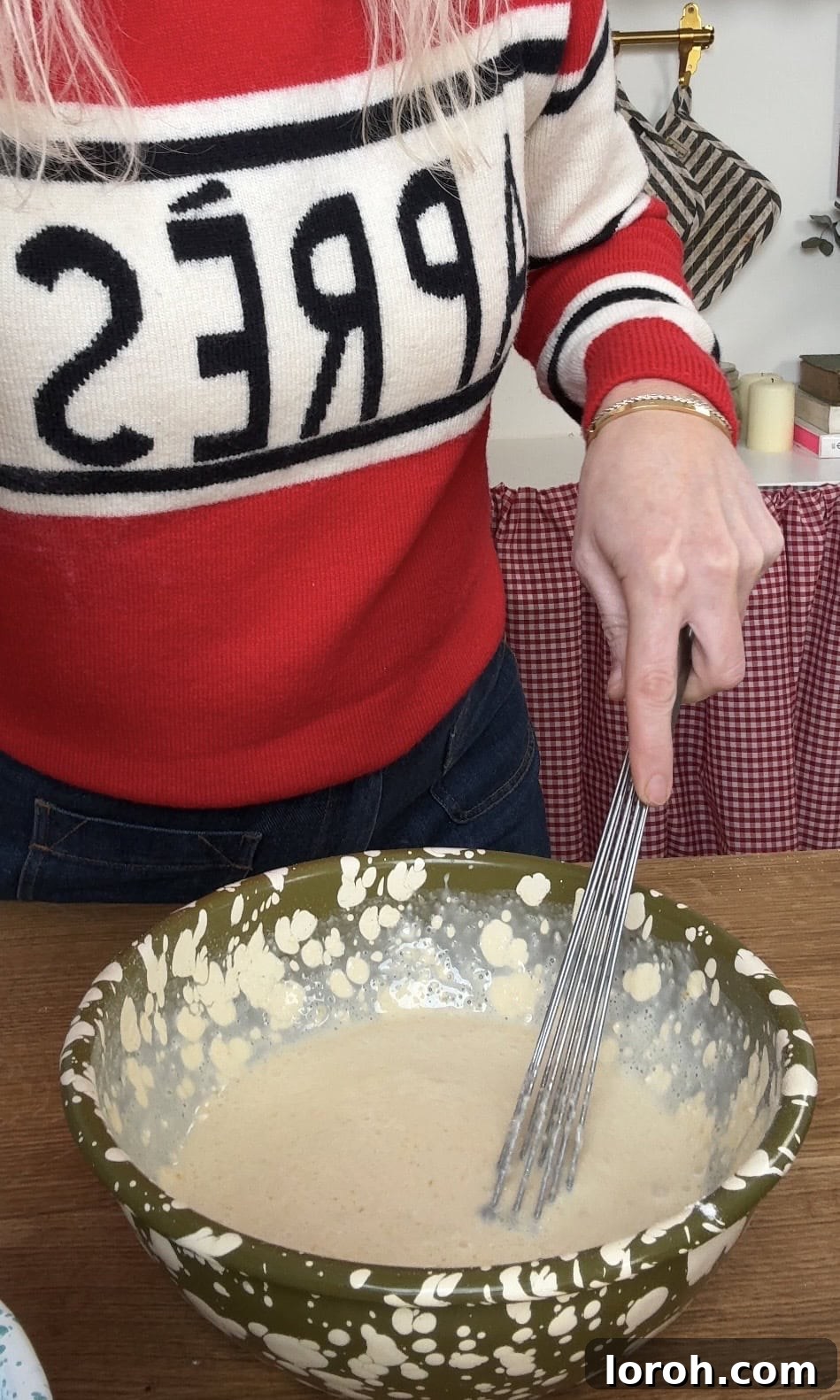 Whisking together the egg yolks, milk, melted butter, sugar, vanilla, salt, and flour to form a smooth batter.