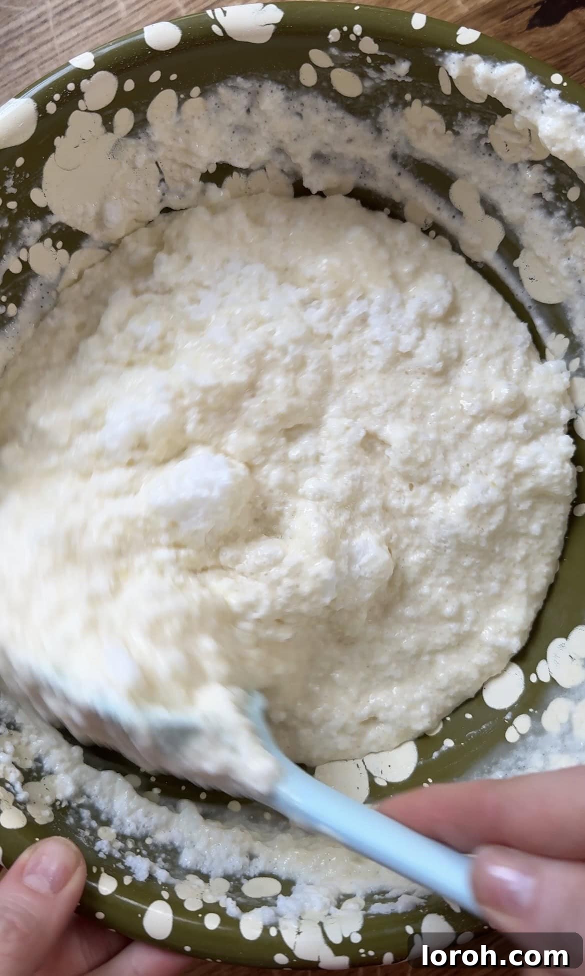 Gently folding the stiffly beaten egg whites into the prepared pancake batter with a large spatula.
